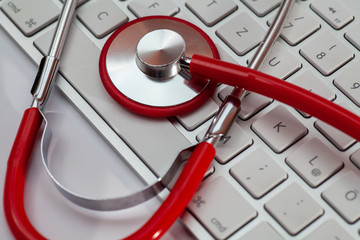 Red doctor's stethoscope on a computer keyboard