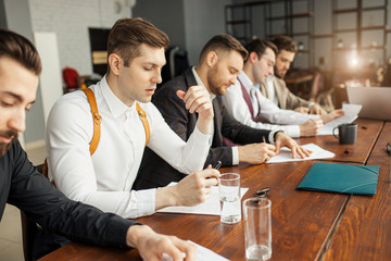 successful, confident business co-workers sit in office and have brainstorming time, thinking about development of their company, how to solve problems connected with finance