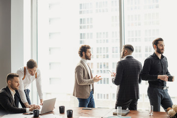 coworking of business team consisted of young successful men wearing formal suits, developing...