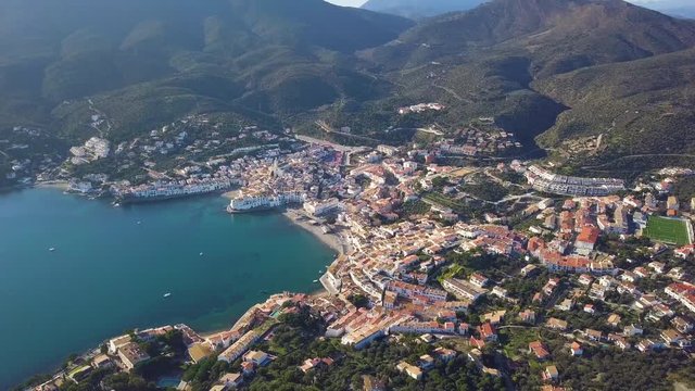 Cadaques Spain. Aerial video. drone is flighting over tiled roofs, narrow streets, white houses and a church. Beautiful blue sea