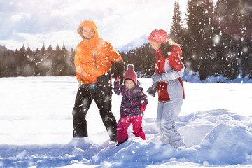 Father And Mother With Their Daughter Playing In The Snow
