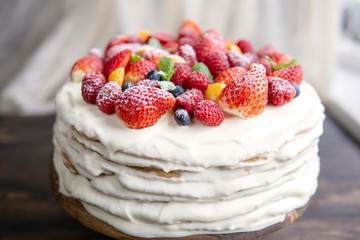 White cream homemade cake decorated with fresh berries, mint, mascarpone cheese on wooden table near window. Close up, copy space, selective focus, natural light. Organic, ecological dessert.