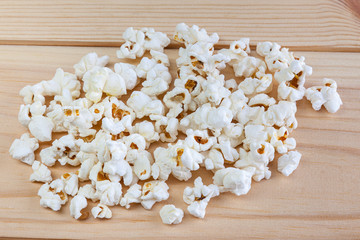Heap of delicious popcorn, on wooden background . Scattered popcorn texture background.