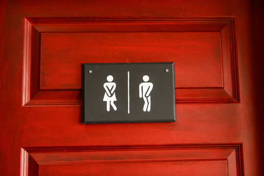 Medium shot of man and lady toilet signs. Restroom funny signs hanged on the wooden red door. Men and women WC sign for the washroom