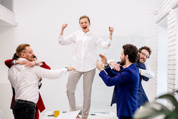 young successful business team enjoy, dance on table after work. confident workers in formal wear celebrating good job, completion of project