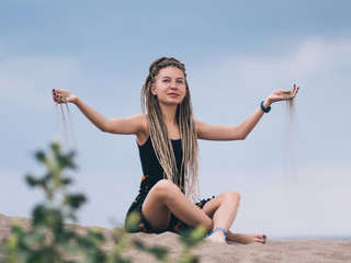 Young woman with dreadlocks pouring sand
