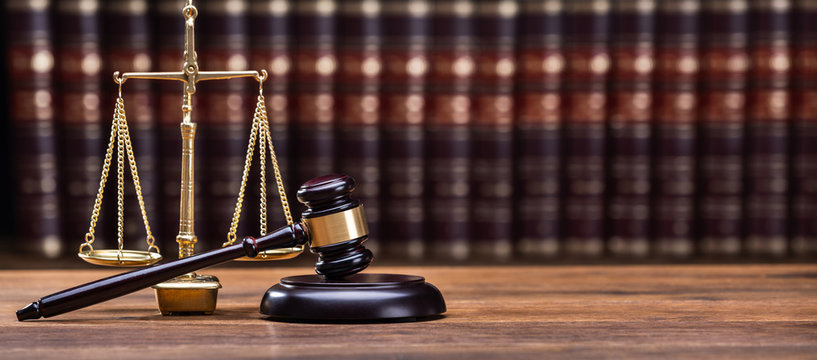 Gavel In Front Of Books With Golden Scale - Powered by Adobe