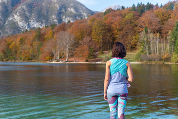 Young woman carrying a child is standing by the Bohinj lake in Slovenia.Young woman carrying a child is standing by the Bohinj lake in Slovenia. Love, parenthood, family.