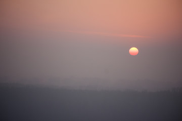 the red sun sets in a gray-pink haze. winter landscape