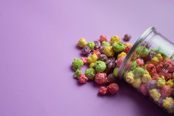 Multicolored fruit flavored popcorn in glass cups on pink background. Candy coated popcorn.
