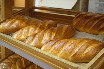 Loafs on a shelf in a bakery close-up. Department of baking bread in the store. Loaves with a brownish brown crust.