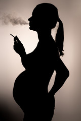 silhouette of a smoking pregnant woman with a cigarette in hand