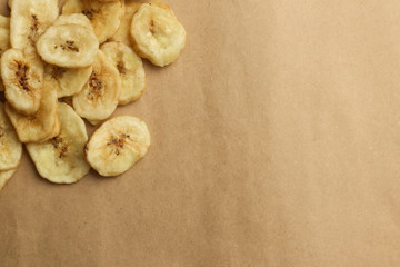 Tasty banana chips on brown background
