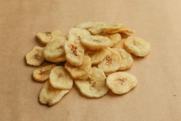 Tasty banana chips on brown background