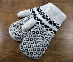 Warm winter mittens on wooden table