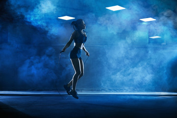 Athletic woman using skipping rope. - obrazy, fototapety, plakaty