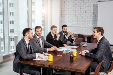 positive business team consisted of young men leaders in tuxedo gathered in office to discuss business ideas and strategies, happy to be a part of successful team. business coworking concept