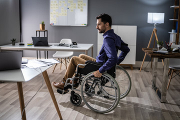 Businessman Sitting On Wheelchair In Office