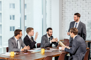 positive business team consisted of young men leaders in tuxedo gathered in office to discuss business ideas and strategies, happy to be a part of successful team. business coworking concept