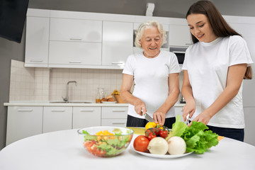 Obraz na płótnie Canvas Senior woman cooking salad with granddaughter.