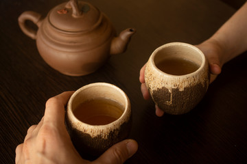 two hands with clay cups with tea and a teapot. top view. Chinese tea ceremony