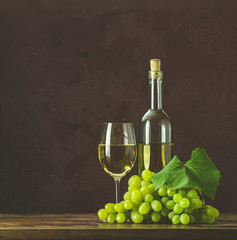 Glasses and bottles of wine and grapes on dark claret bordeaux concrete surface background