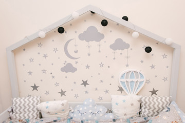 Wooden grey white baby bed in the shape of a house with stars and moon on the wall, wooden night light in the form of a balloon, children's room decor