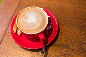 coffee-break. Red cup of cappuccino with beautiful latte art on old wooden background. Latte art coffee.aroma coffee in red ceramic cup. Copy space.wood table in cafe, restaurant
