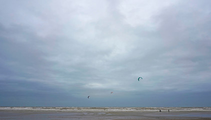 Beach on a cloudy winter day, some kite surfers on it, Camber Sands, England 