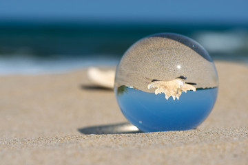 Lensball summer vacation landscape with starfish reflection. Travel and leasure concept. Selective focus, copy space.