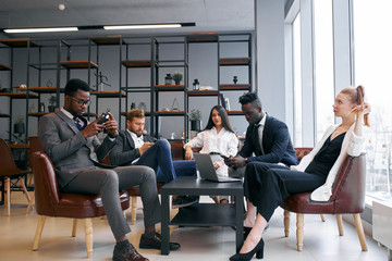 Fototapeta premium African american handsome businessman in tuxedo talking with business partners in office, telling how to be successful