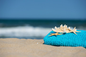 Fototapeta na wymiar Summer vacation concept towel with sunglasses and starfish on sandy tropical beach - selective focus, copy space