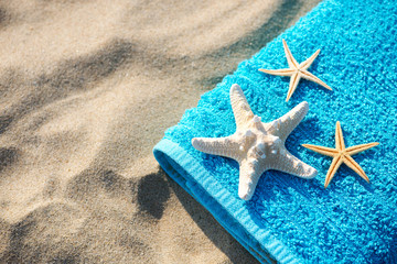 Fototapeta na wymiar Summer vacation concept towel with sunglasses and starfish on sandy tropical beach - top view, copy space