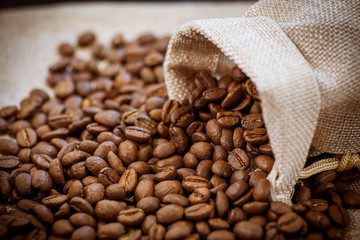 Black roasted coffee beans in a bag.  Coffee beans spilled out of a small bag.