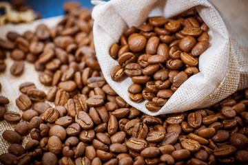 Black roasted coffee beans in a bag.  Coffee beans spilled out of a small bag.