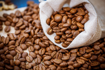 Black roasted coffee beans in a bag.  Coffee beans spilled out of a small bag.