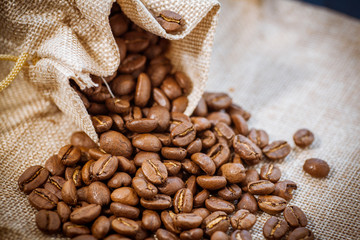 Cafe beans get enough sleep from their bag on a sackcloth background. Black coffee beans close-up. Roasted coffee beans background.