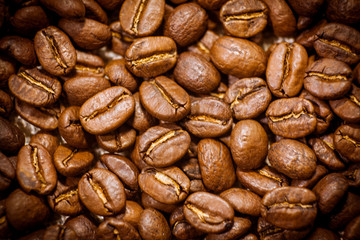 Black coffee beans close-up. Roasted coffee beans background. Brown coffee beans isolated on burlap background.