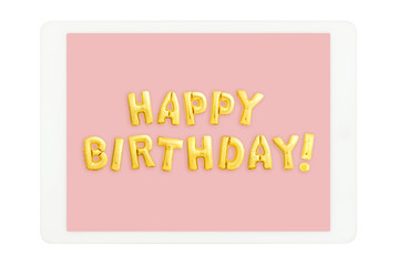 White tablet computer with golden HAPPY BIRTHDAY words made of inflatable balloons isolated on white background. Birthday concept