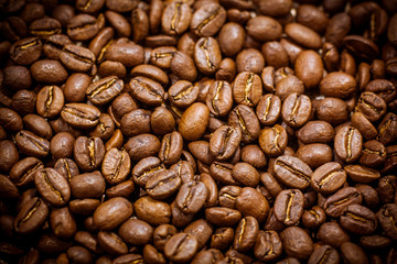 Black coffee beans close-up. Roasted coffee beans background. Brown coffee beans isolated on burlap background.