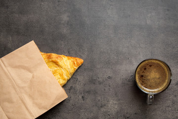 Samsa in paper envelope and coffee in glass cup on gray background top view