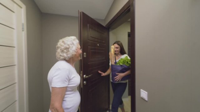 Old woman opening door to granddaughter.