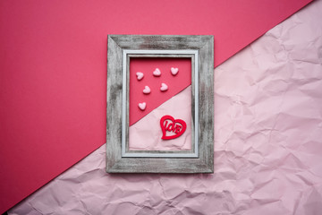 Valentines day copy space. Pink and red Heart shape beads on pink background with wooden frames. 