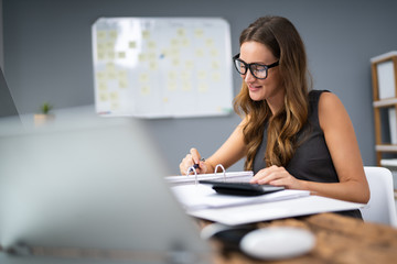 Smiling Businesswoman Calculating Tax
