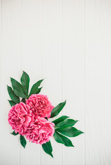Festive pink peony flower composition on the white wooden background. Floral texture mockup. Flat lay, overhead, top view. Vertical card. Vintage, retro toning image. Copy space.