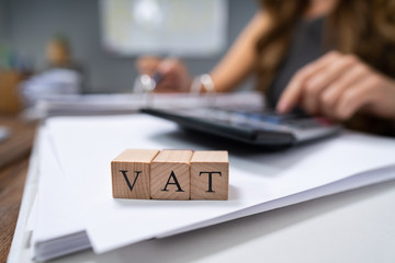 Businessperson's Hand Calculating VAT With Calculator