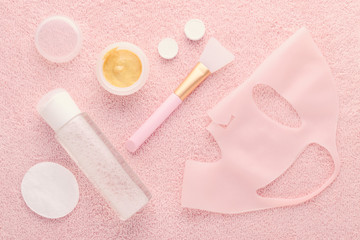 golden facial cream mask with a brush, micellar water and silicone beauty mask on pink background