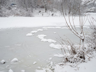 View of the snow-covered pond in the city park.
