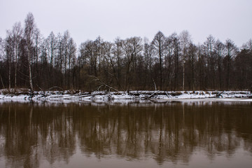 Winter landscape with river and reflections and snow on the Bank on a cloudy day