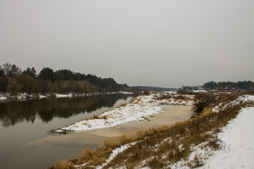Winter landscape with river and reflections and snow on the Bank on a cloudy day